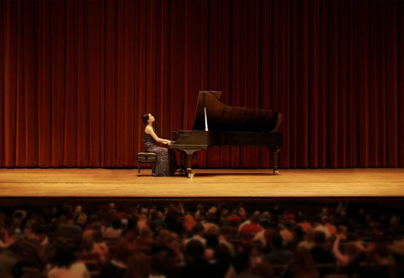 Shot of a young woman playing the piano during a musical concert